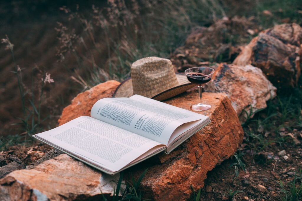 A tranquil outdoor setting with an open book, hat, and wineglass on rocks in rural Oax., México.
